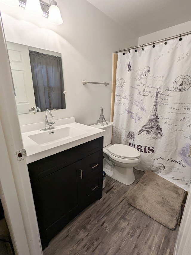 full bath featuring toilet, curtained shower, wood finished floors, and vanity