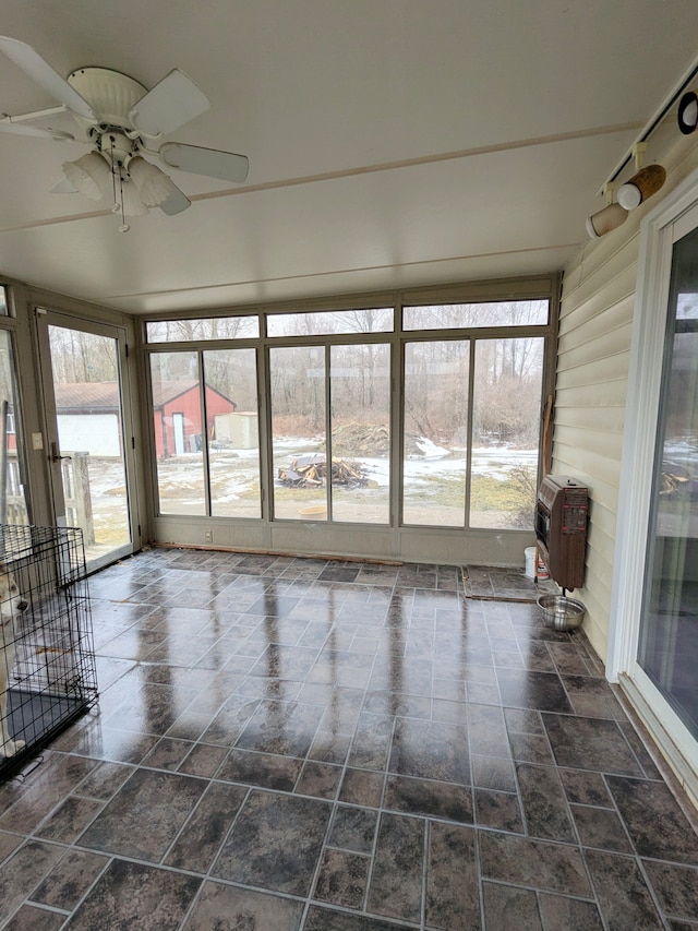 unfurnished sunroom featuring a water view, a ceiling fan, and heating unit