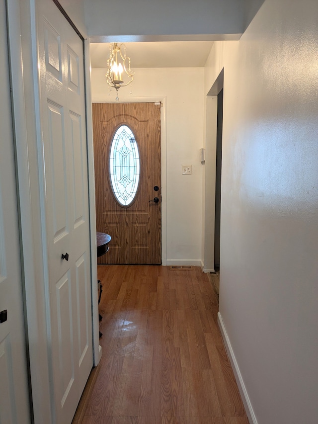 entryway featuring a notable chandelier, baseboards, and wood finished floors