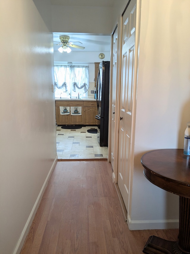 corridor with light wood-type flooring and baseboards