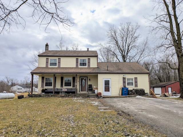 view of front of house featuring a porch, a front yard, a chimney, and aphalt driveway