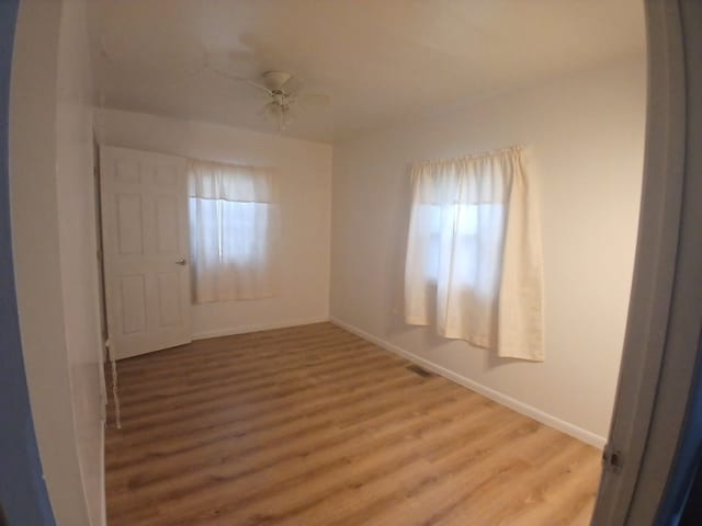 unfurnished room featuring a ceiling fan, visible vents, baseboards, and wood finished floors