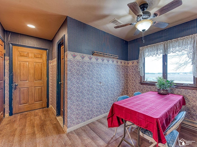 dining room with wallpapered walls, visible vents, and wood finished floors