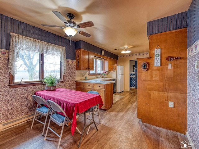 kitchen with light countertops, light wood finished floors, brown cabinetry, and a sink