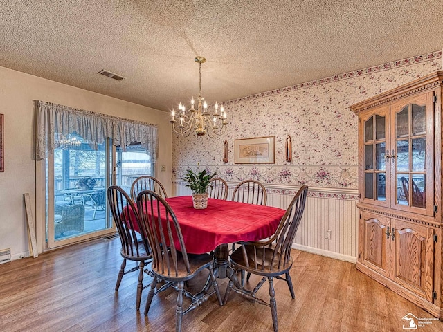 dining space featuring visible vents, a textured ceiling, and wallpapered walls