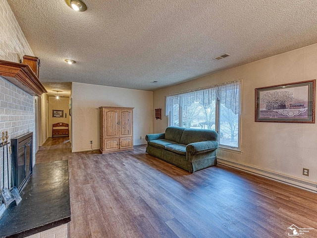 living area featuring a textured ceiling, a fireplace, wood finished floors, and visible vents