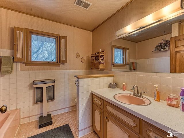 full bathroom featuring wallpapered walls, visible vents, a wainscoted wall, ornamental molding, and vanity