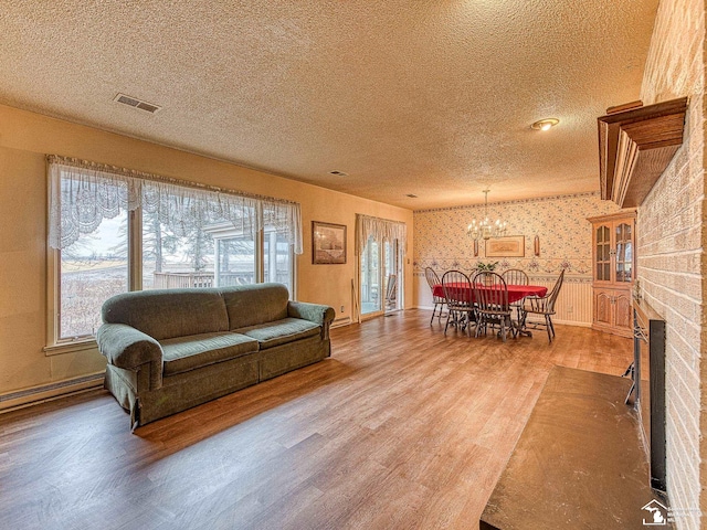 living room with a fireplace, visible vents, a textured ceiling, wood finished floors, and wallpapered walls