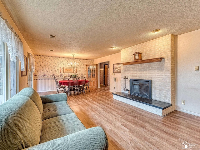 living area with baseboards, visible vents, wood finished floors, a textured ceiling, and a fireplace