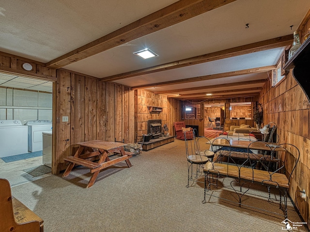 living room featuring light carpet, washer and clothes dryer, beam ceiling, and wooden walls