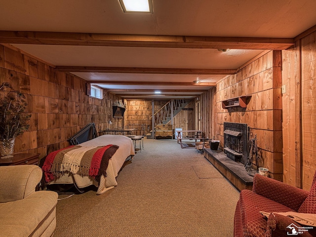 carpeted bedroom featuring beam ceiling, a fireplace, and wooden walls