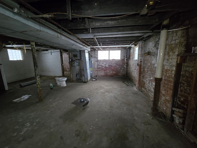 basement featuring water heater and brick wall