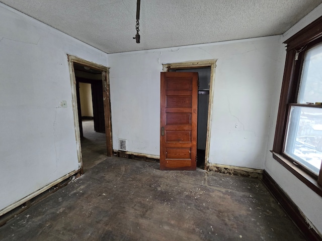 unfurnished room with a textured ceiling, visible vents, and a healthy amount of sunlight