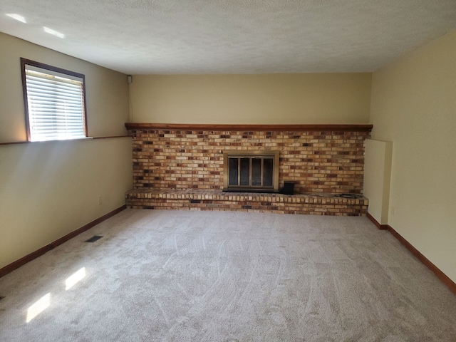 unfurnished living room with a textured ceiling, a fireplace, carpet flooring, visible vents, and baseboards