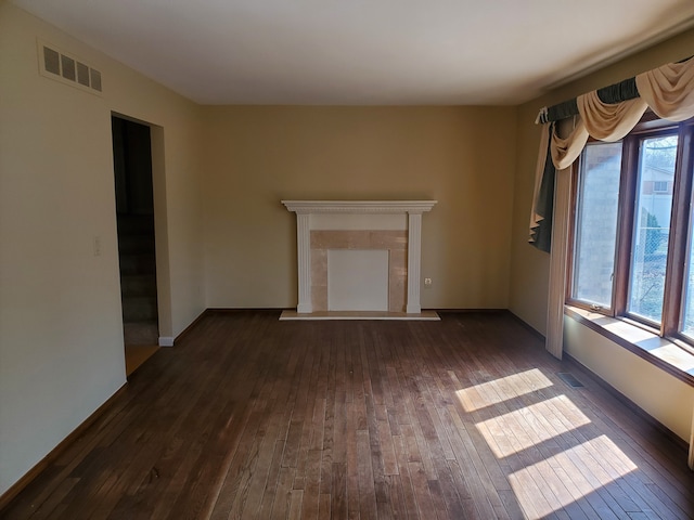 unfurnished living room with dark wood-style floors, visible vents, and a wealth of natural light