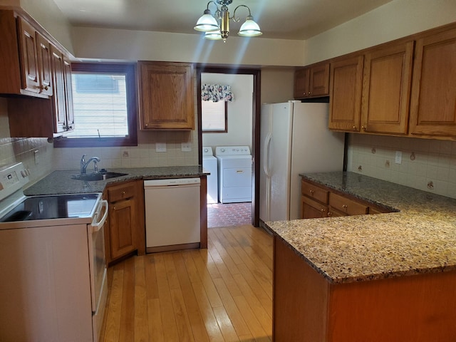 kitchen featuring light wood-style flooring, white appliances, a sink, independent washer and dryer, and brown cabinetry