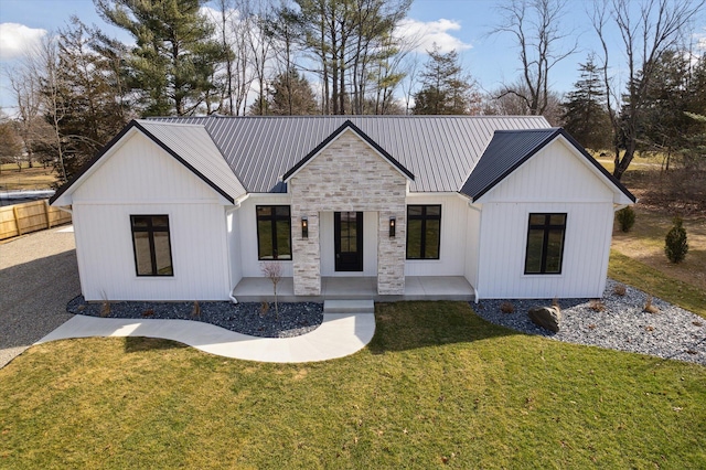 modern inspired farmhouse with metal roof, stone siding, and a front yard