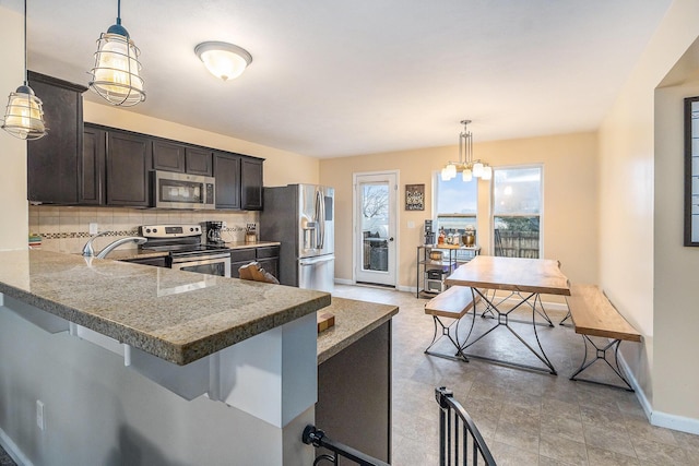 kitchen with a breakfast bar area, dark brown cabinetry, stainless steel appliances, hanging light fixtures, and backsplash