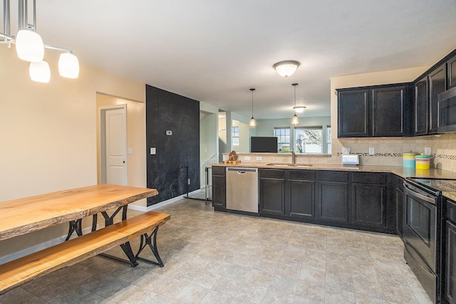 kitchen with dark cabinets, a sink, appliances with stainless steel finishes, backsplash, and decorative light fixtures