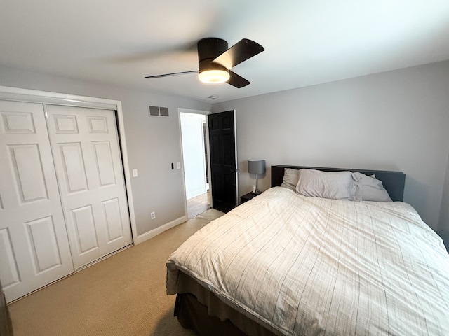 bedroom with visible vents, baseboards, ceiling fan, light colored carpet, and a closet