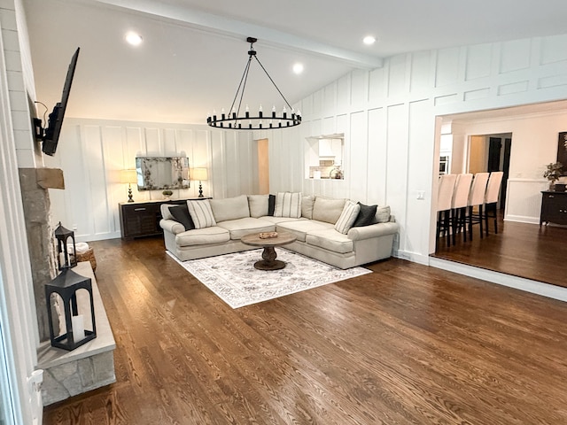 living area with dark wood finished floors, an inviting chandelier, a decorative wall, and vaulted ceiling with beams