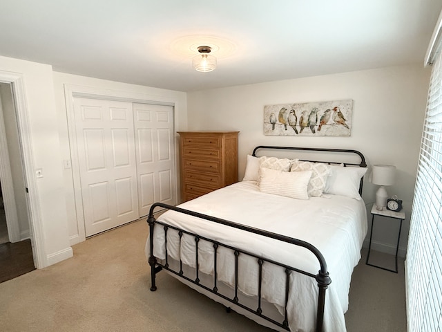 bedroom featuring light carpet, baseboards, and a closet