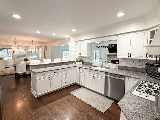 kitchen featuring stainless steel dishwasher, a peninsula, plenty of natural light, and a sink