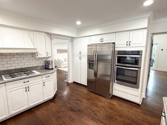 kitchen with premium range hood, dark wood-type flooring, tasteful backsplash, stainless steel appliances, and crown molding