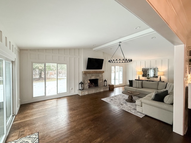 living area featuring a stone fireplace, lofted ceiling with beams, and dark wood-type flooring