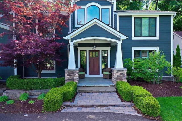 view of exterior entry with covered porch and stone siding