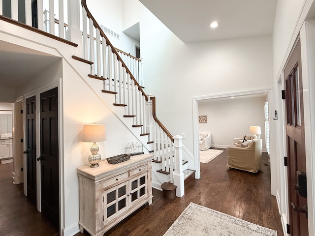 entryway with visible vents, a high ceiling, dark wood-style floors, and stairway