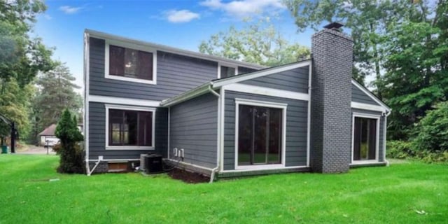 rear view of property featuring central AC unit, a lawn, and a chimney