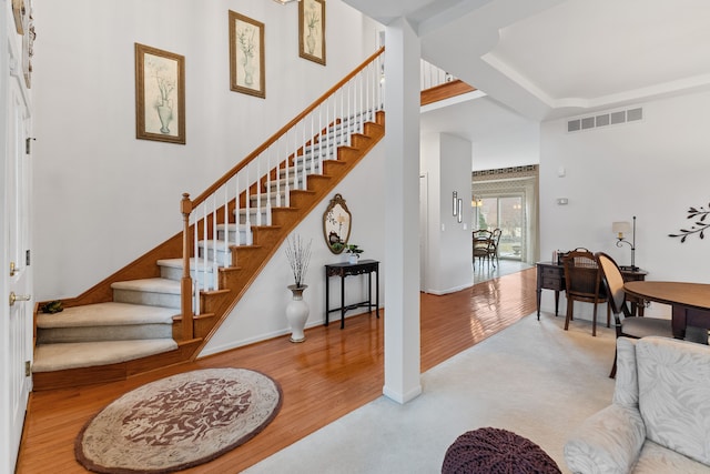 foyer entrance featuring wood finished floors, visible vents, baseboards, and stairs