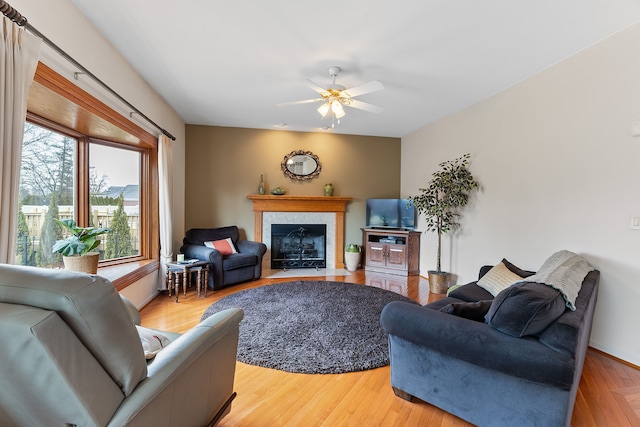 living area with a fireplace with flush hearth, ceiling fan, and wood finished floors