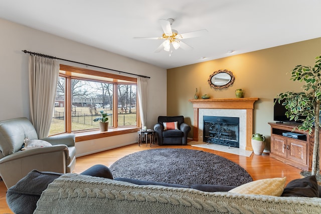 living room featuring a ceiling fan, wood finished floors, and a high end fireplace