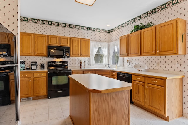 kitchen with light countertops, visible vents, a sink, black appliances, and wallpapered walls