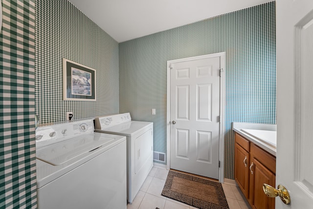 washroom with cabinet space, a sink, washer and clothes dryer, and light tile patterned floors