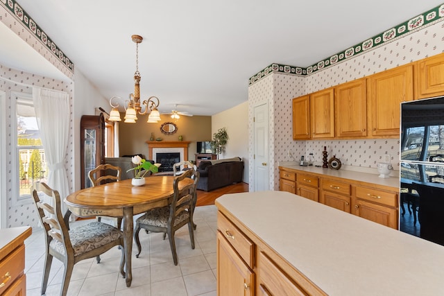 kitchen featuring a chandelier, a glass covered fireplace, light countertops, and fridge