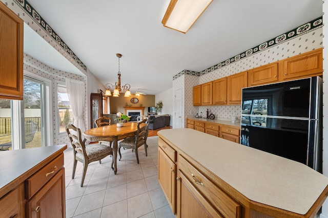 kitchen featuring light tile patterned floors, hanging light fixtures, light countertops, freestanding refrigerator, and wallpapered walls