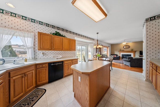 kitchen with light countertops, a center island, dishwasher, a glass covered fireplace, and wallpapered walls