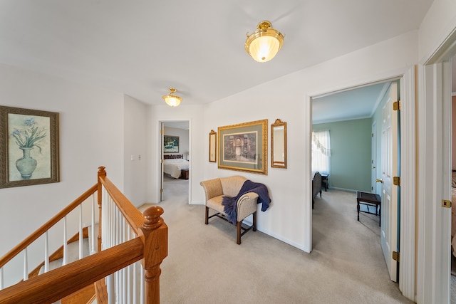 hallway featuring baseboards, light carpet, and an upstairs landing