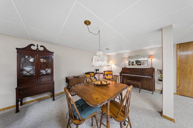 dining area with light carpet, a paneled ceiling, and baseboards