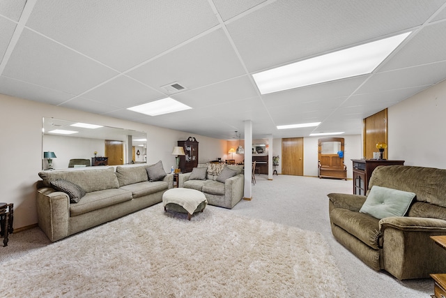 living area with carpet, visible vents, and a paneled ceiling