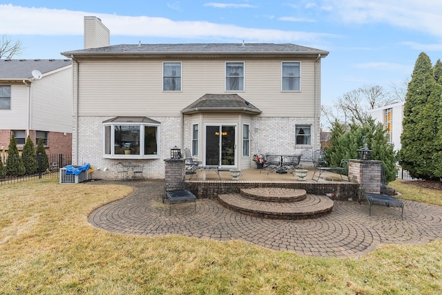 back of property with brick siding, a patio, a chimney, a lawn, and fence