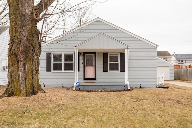 bungalow featuring an outdoor structure, concrete driveway, a front yard, and fence