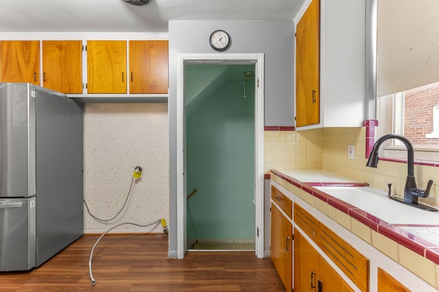 kitchen featuring tile counters, dark wood-type flooring, a sink, and freestanding refrigerator