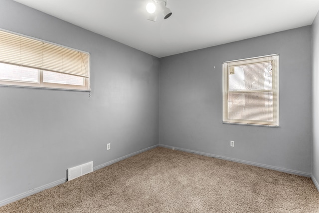 spare room featuring carpet flooring, visible vents, and baseboards