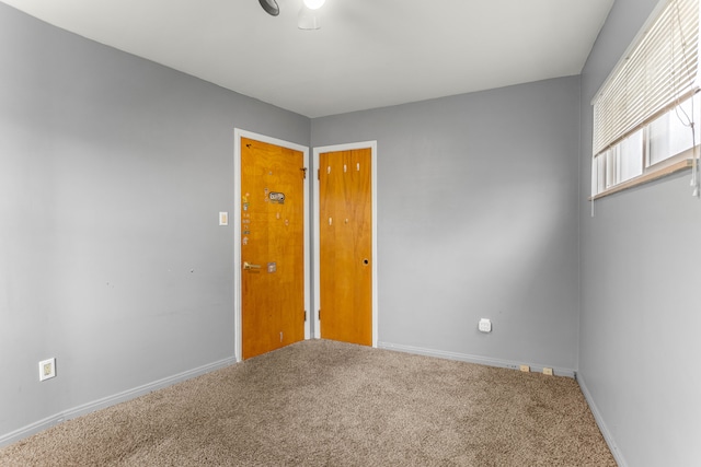 carpeted empty room featuring baseboards