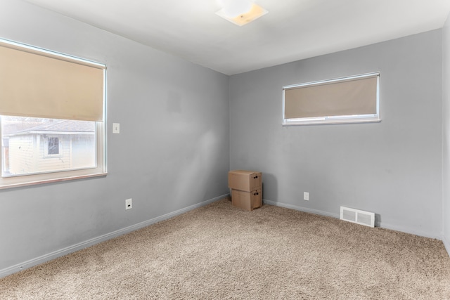 carpeted empty room featuring baseboards and visible vents