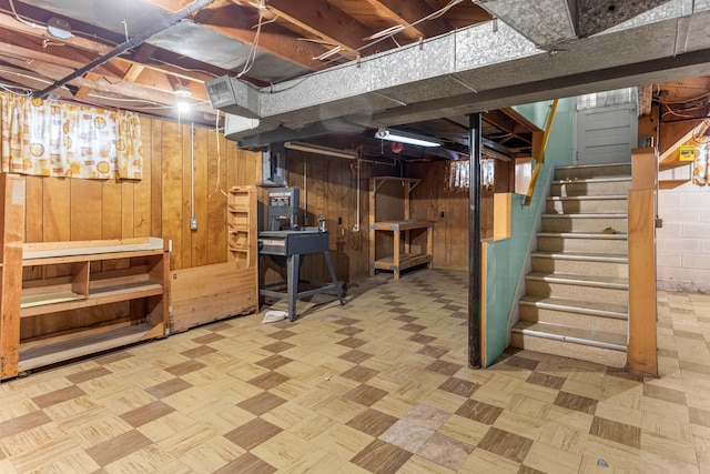 unfinished basement featuring wooden walls and stairs